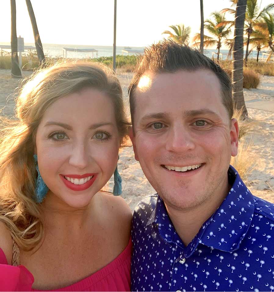 Michael and Shannon smiling with palm trees in the background