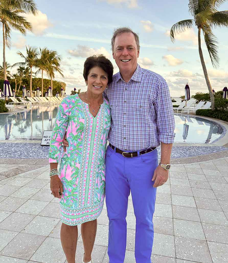 Tom and Lisa smiling with palm trees in the background